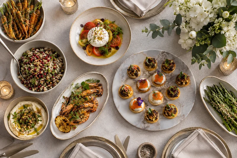 An elegant table of canapés, grilled chicken and colourful vegetable dishes