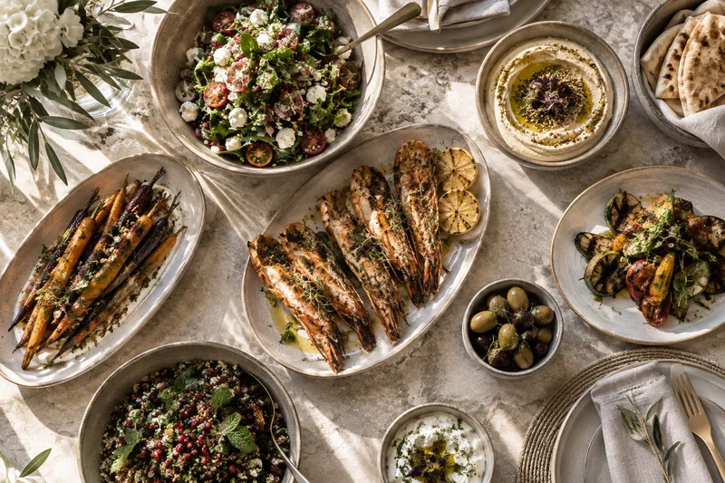 An overhead villa dining spread with grilled chicken, vegetables and salads