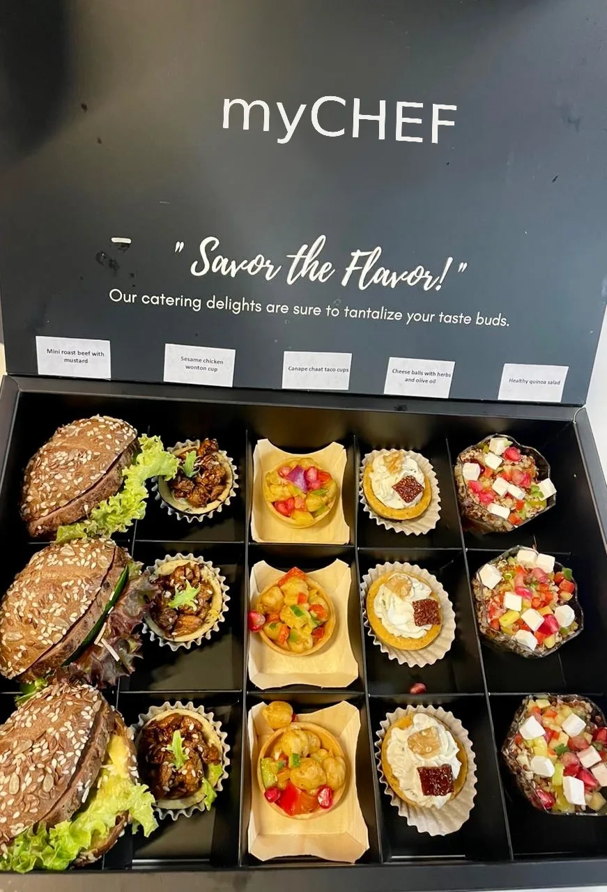 Assorted boxed canapés with sandwiches and bite-sized dishes.