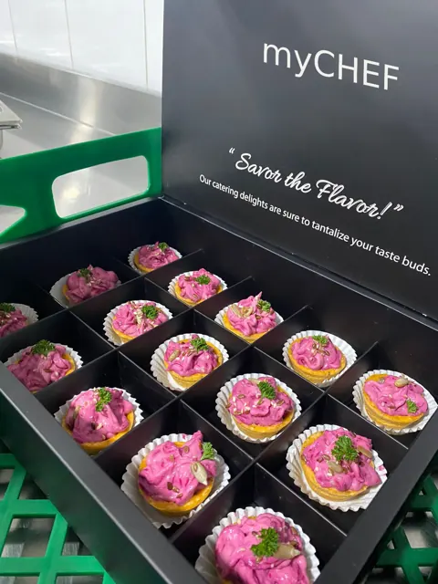 Boxed canapés topped with bright pink garnish.
