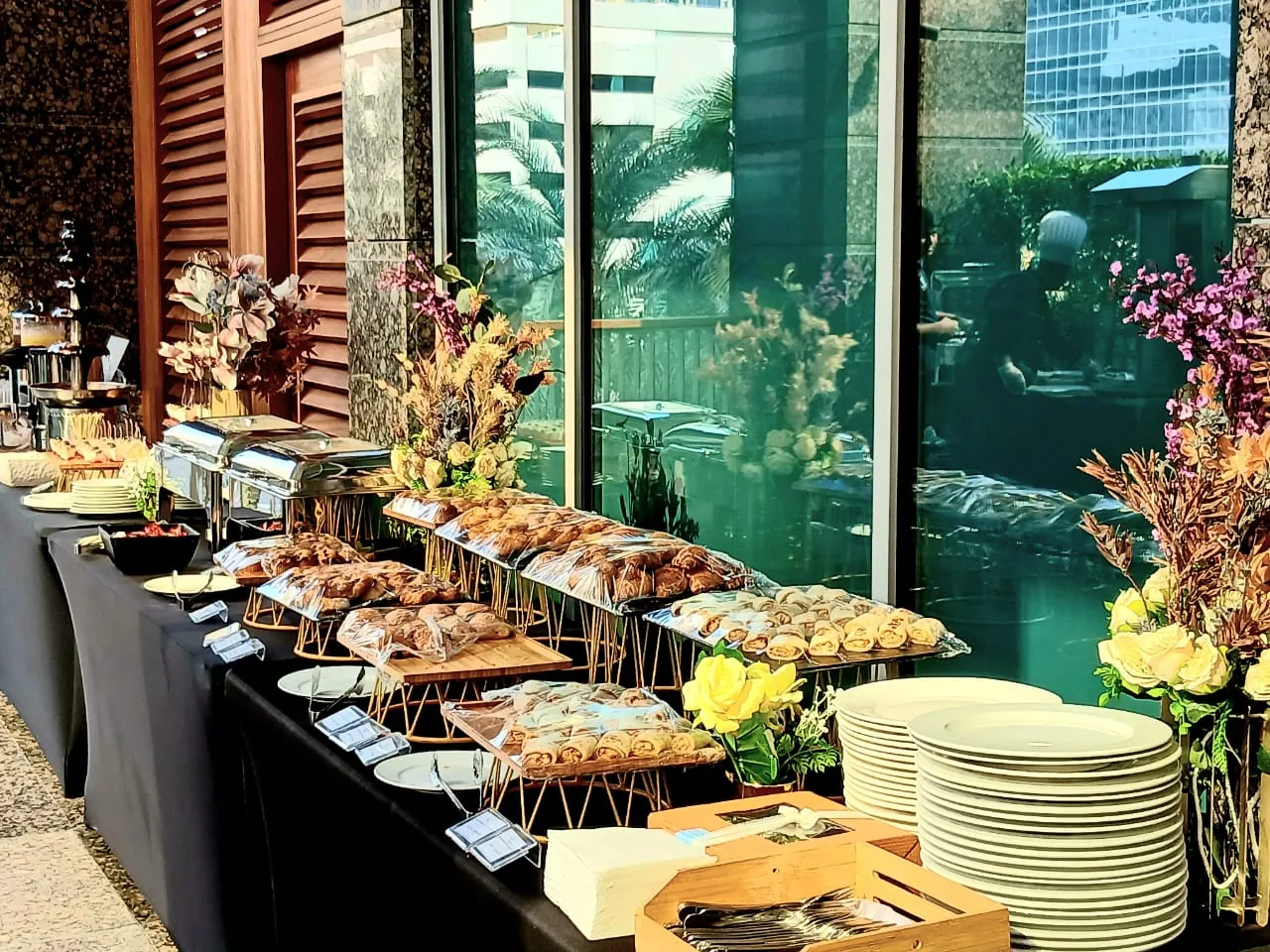 Breakfast buffet beside windows with pastries, fruit and warm dishes.