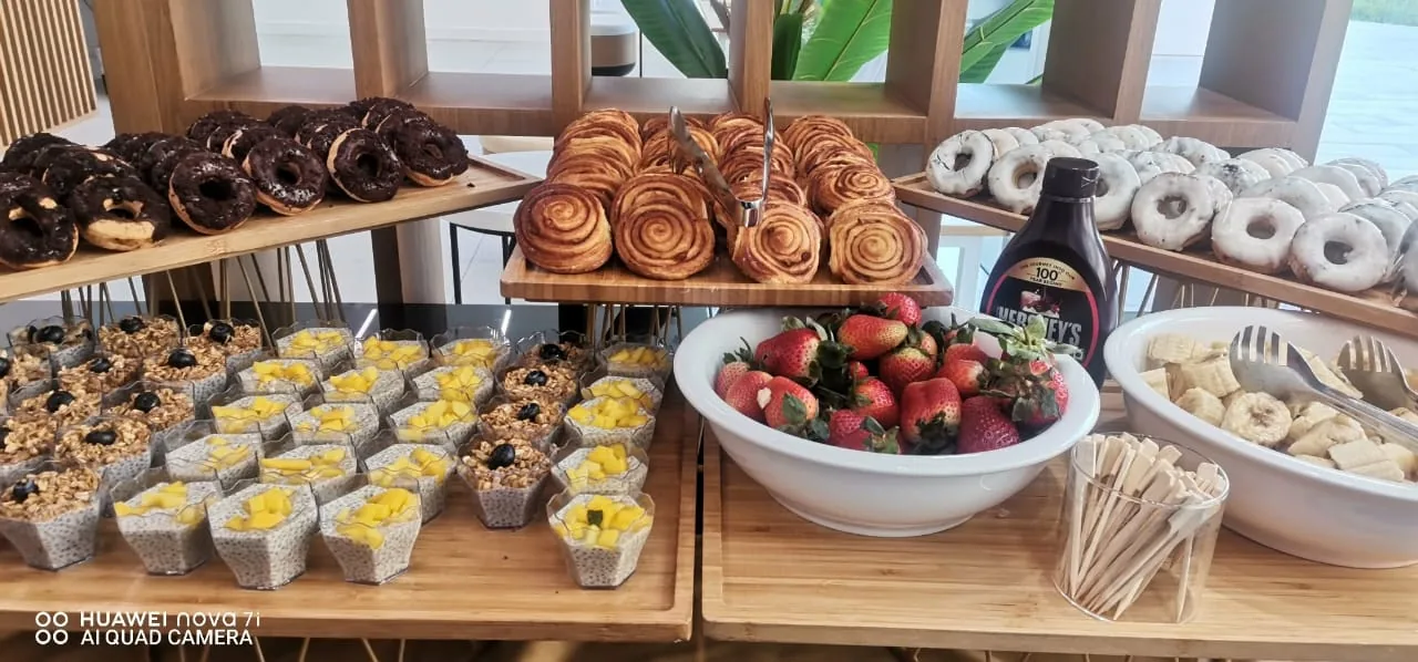 Breakfast pastry display with doughnuts, croissants and muffins.