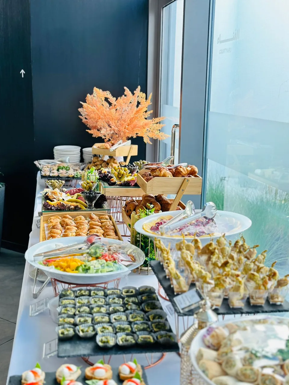 Buffet table with salads, canapés and fresh floral arrangements.
