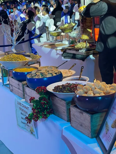 Chaat station with bowls of toppings during an evening event.