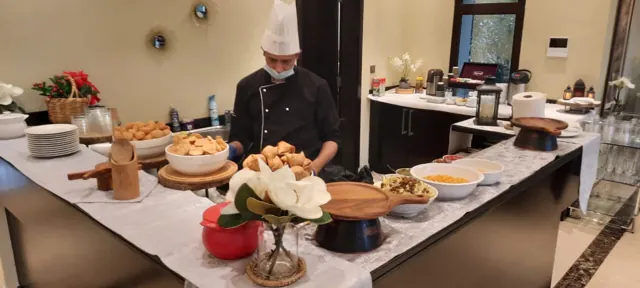 Chef at a chaat station with serving bowls and floral details.
