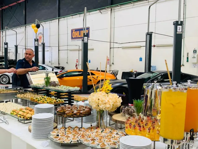 Chef behind a breakfast buffet with juice dispensers and plates.