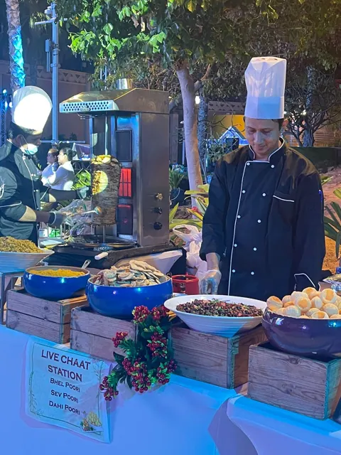 Chef behind a live chaat station at an evening event.