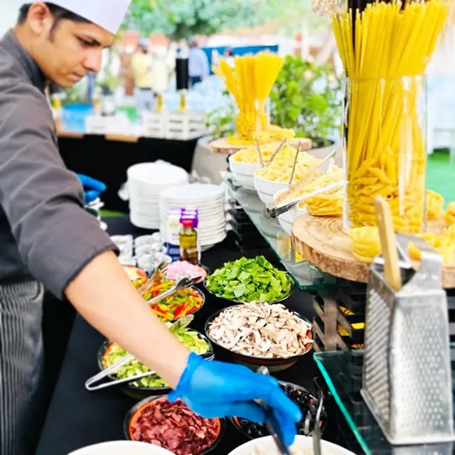 Chef preparing food at a live pasta counter.