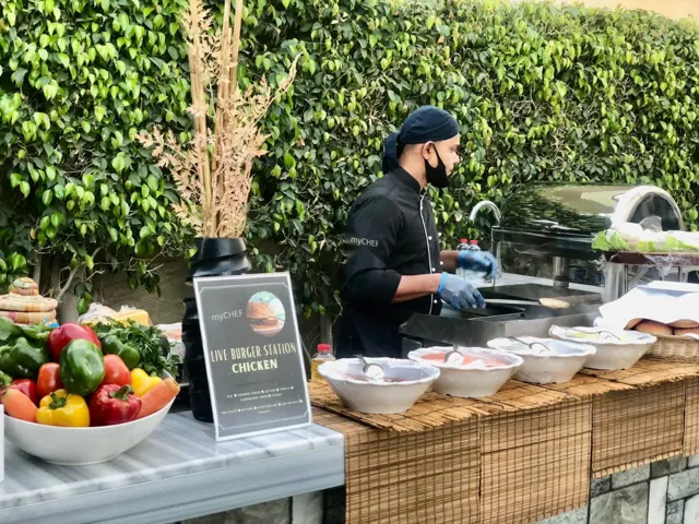 Chef preparing food at an outdoor burger station.