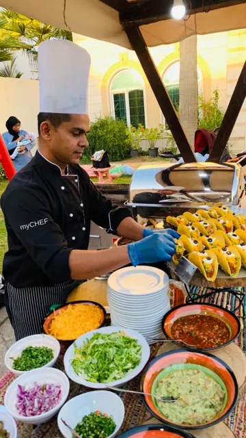Chef with a Mexican taco spread and assorted sauces.