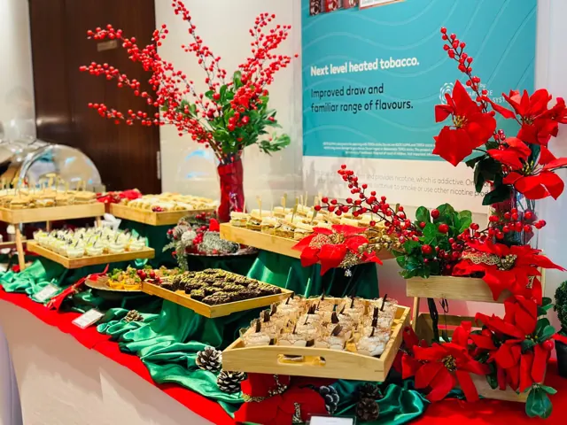 Christmas catering display with red flowers and green table styling.