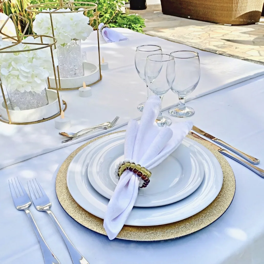 Close view of a white and gold place setting on a garden table.