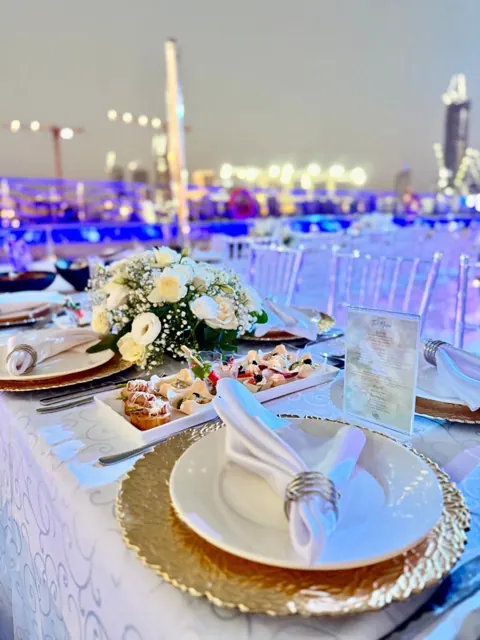 Close view of a white and gold place setting on a yacht deck.