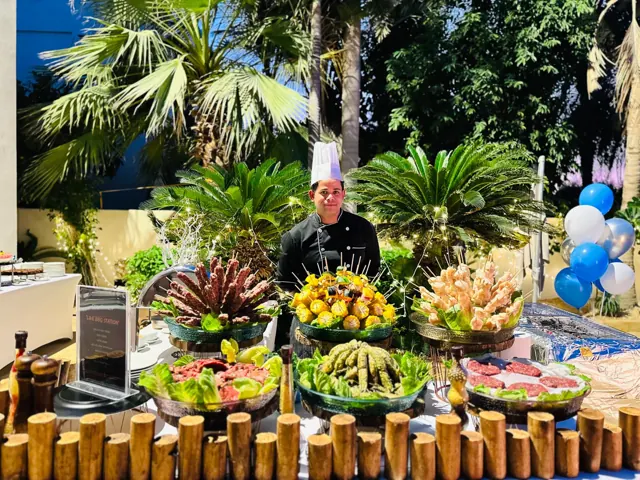 Garden BBQ display with skewers, salads and a chef ready for service.