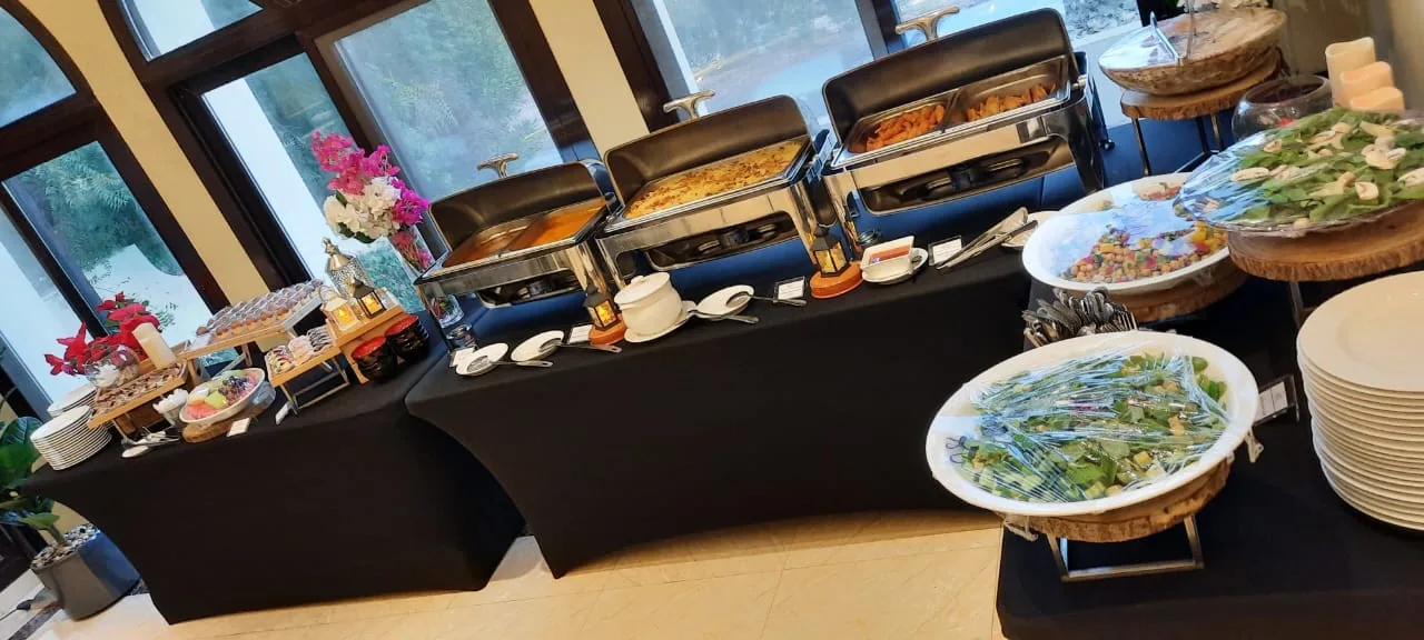 Indoor buffet with salads, serving dishes and stacked plates.
