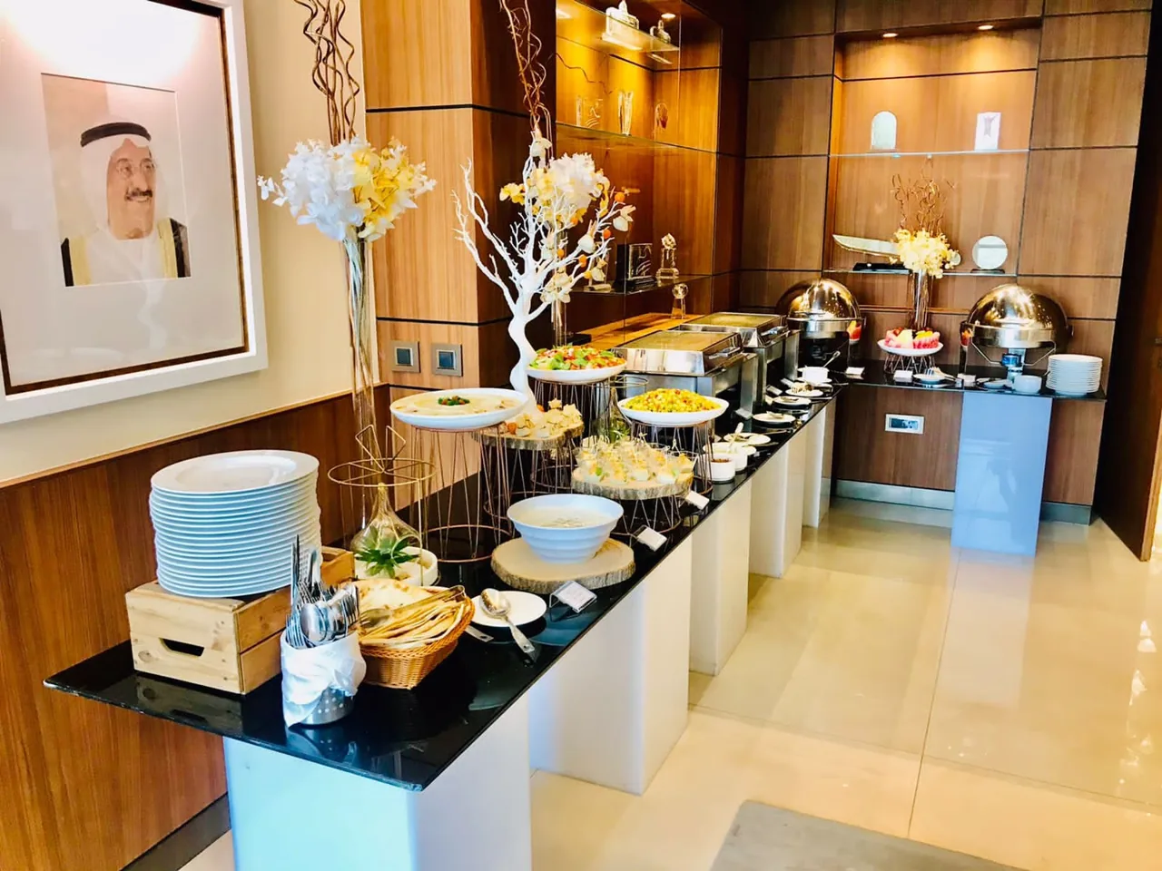 Indoor catering buffet with salads, warm dishes and serving plates.
