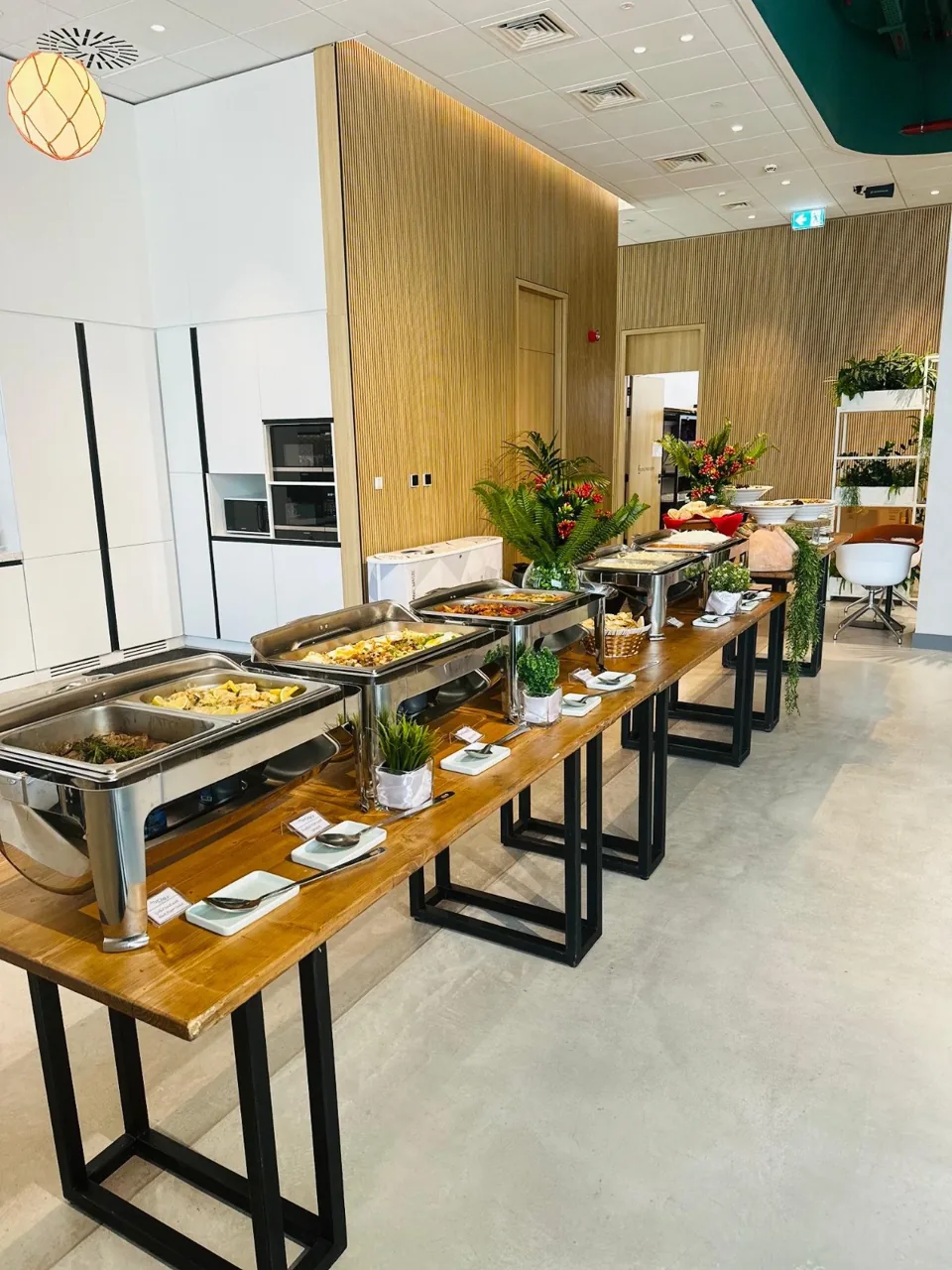 Long catered buffet with flowers and covered chafing dishes.