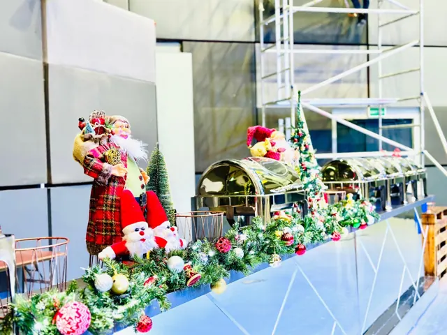 Long Christmas buffet table decorated with garlands and festive figures.
