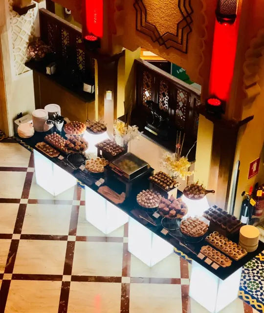 Long dessert display with assorted sweets in a warm indoor setting.