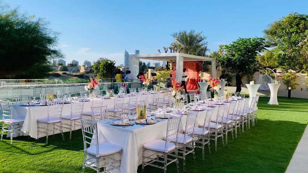 Long garden tables set for a daytime outdoor celebration.