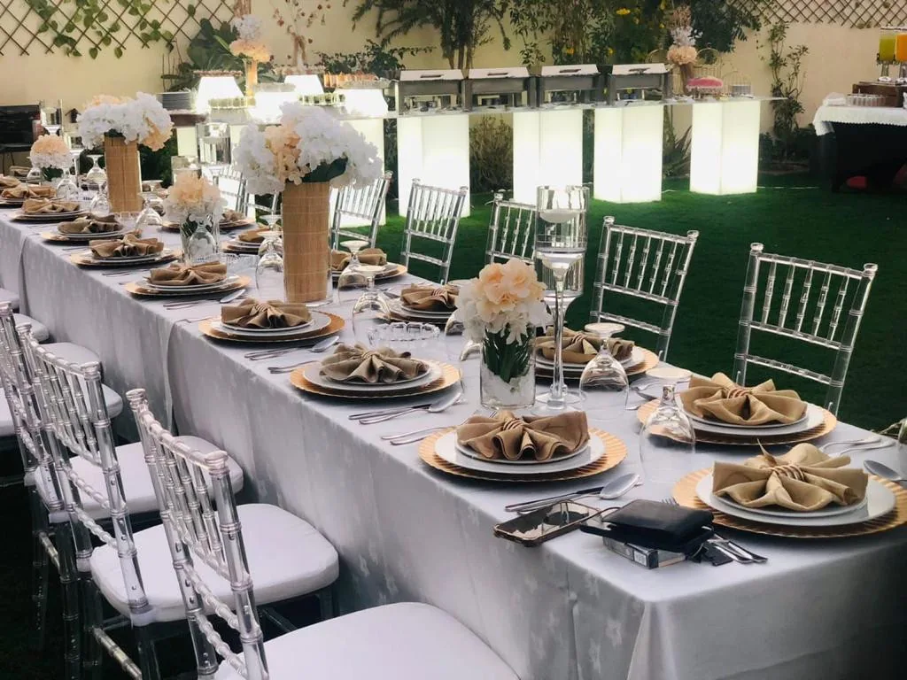 Long outdoor dining table with neutral linen and floral arrangements.