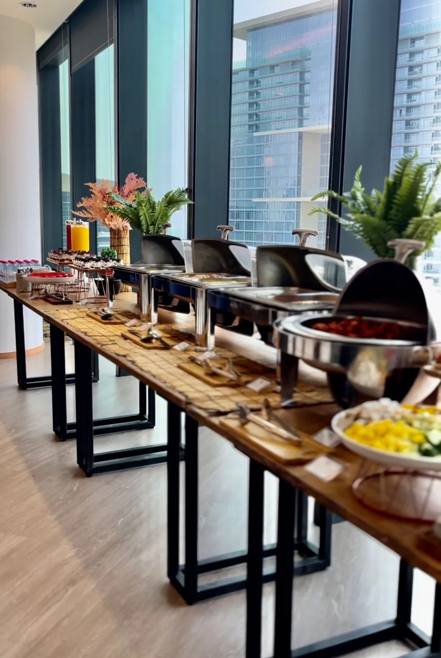 Long row of warm buffet dishes with a chef at the far end.