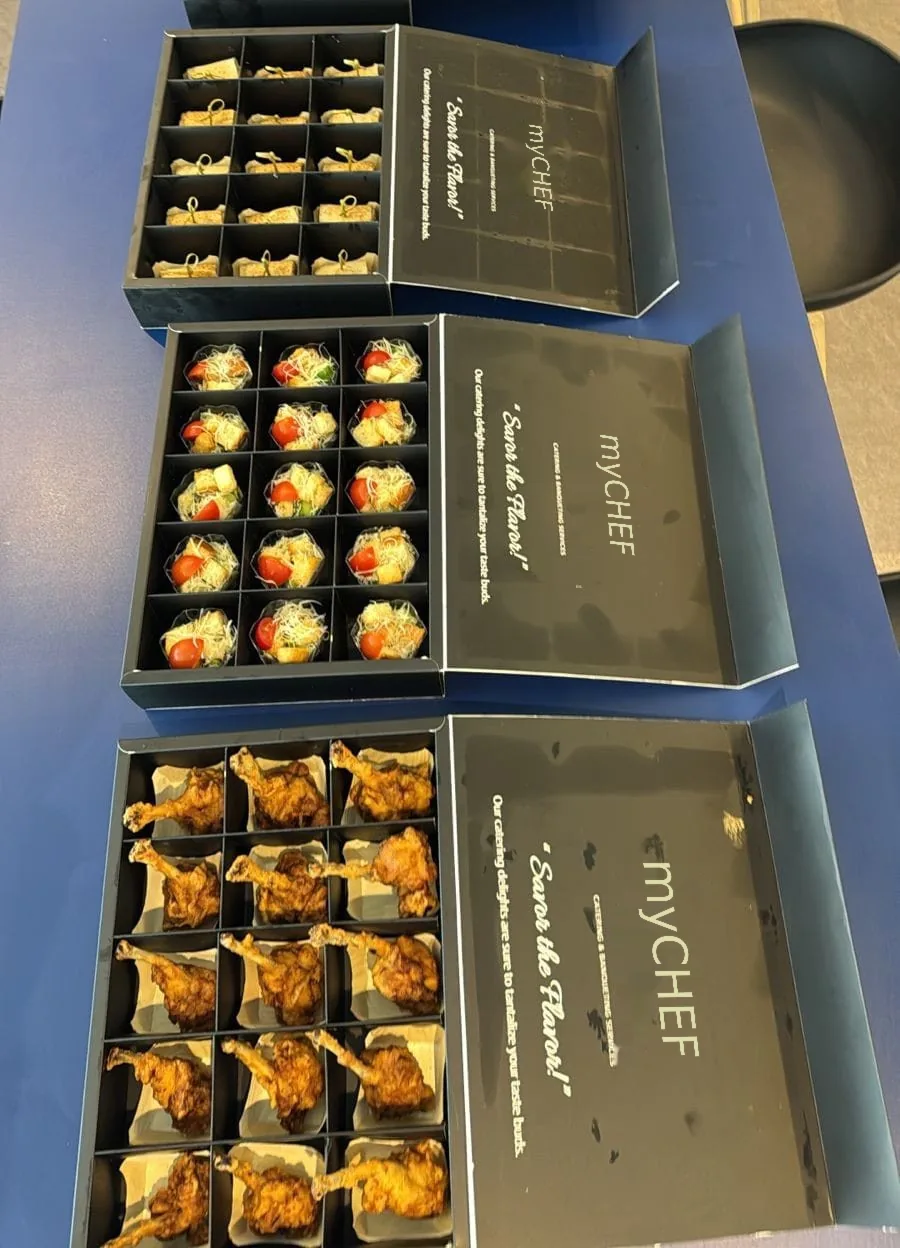 Mixed catering platters in branded presentation boxes.