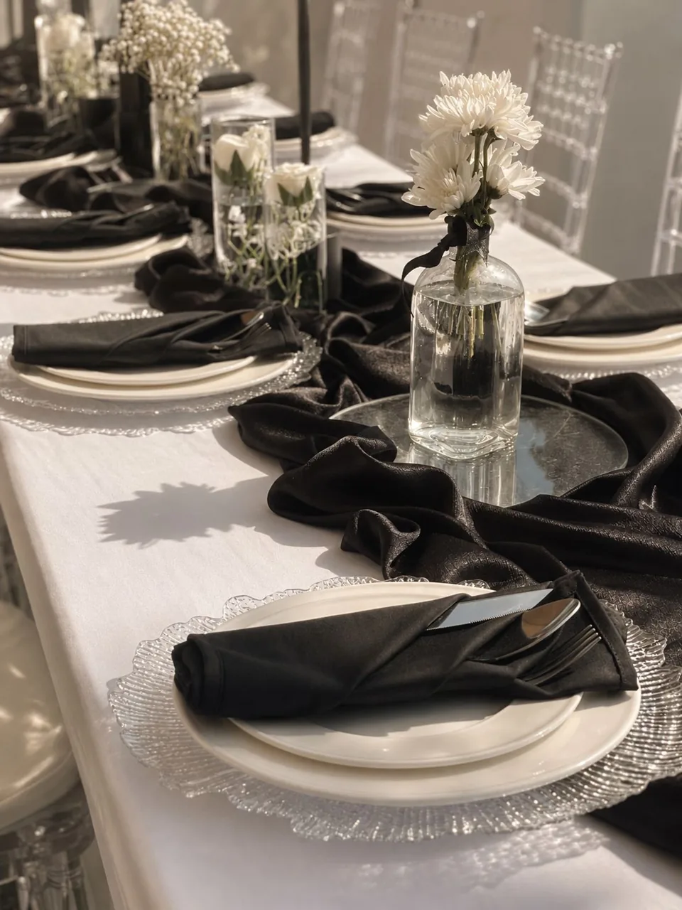 Monochrome table setting with dark napkins and fresh flowers.