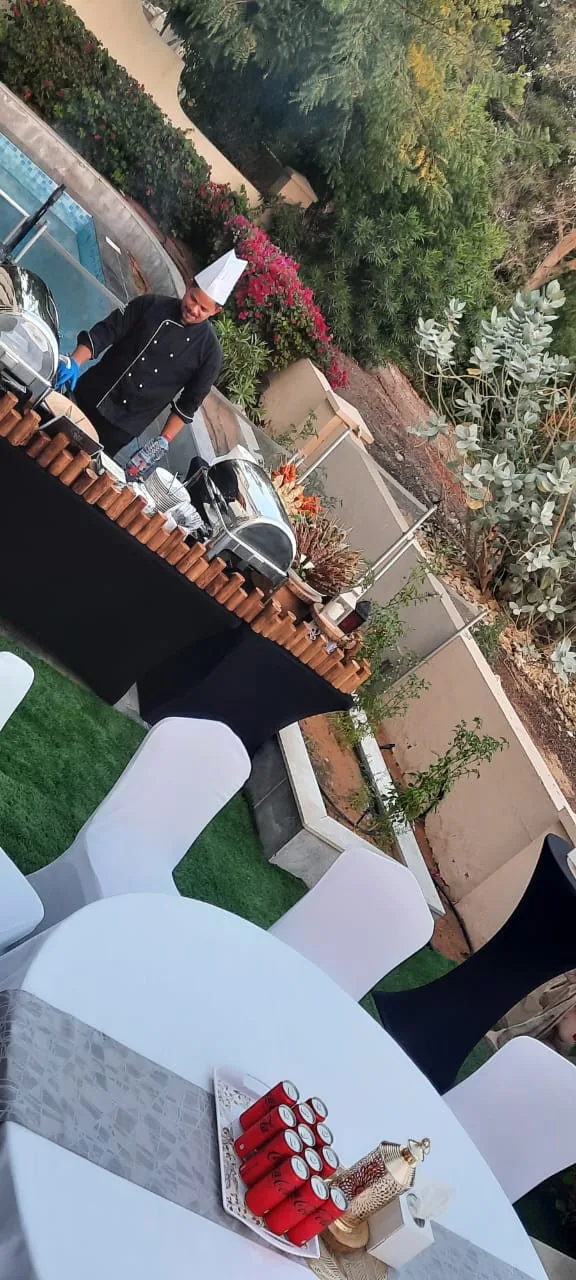 Outdoor buffet tables set beside a villa garden.
