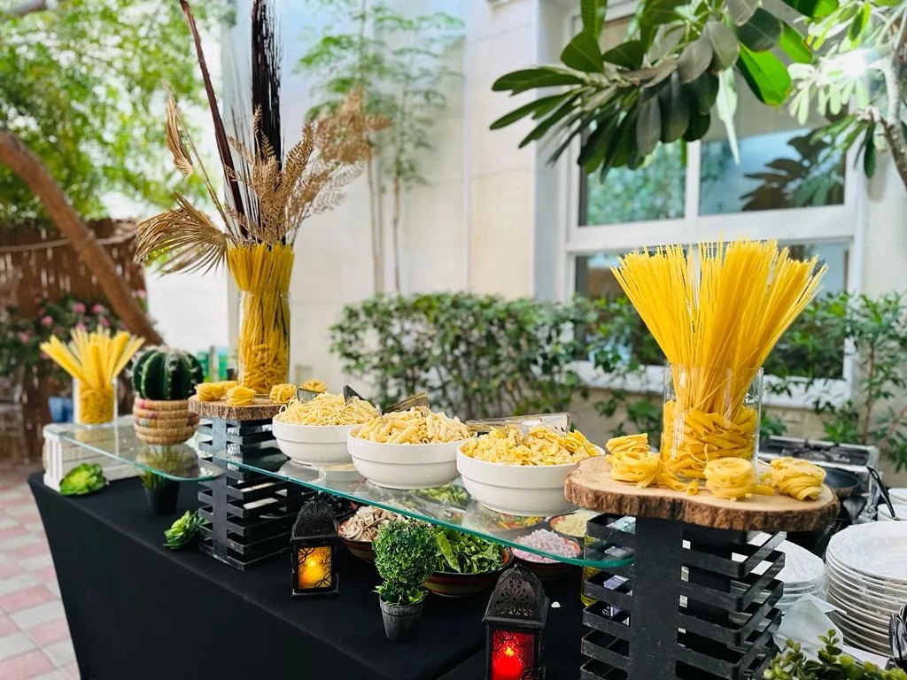 Outdoor pasta buffet with pasta varieties, sauces and herbs.