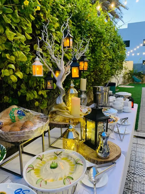 Outdoor Ramadan buffet with white linen and warm chafing dishes.