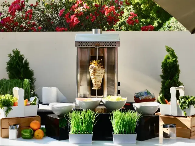 Outdoor shawarma station with sauces, vegetables and serving bowls.