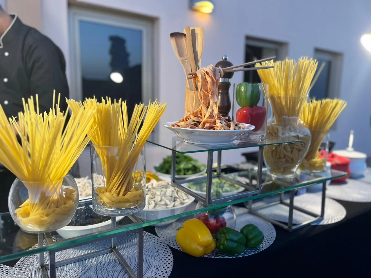 Pasta station with dry pasta varieties and ingredient bowls.