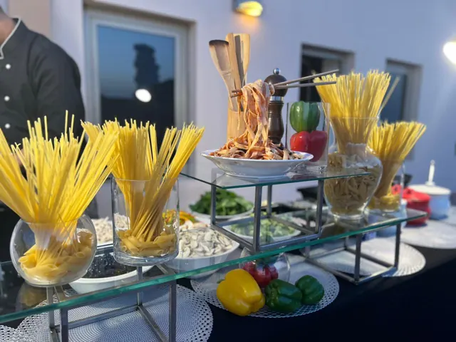 Pasta station with dry pasta varieties and ingredient bowls.