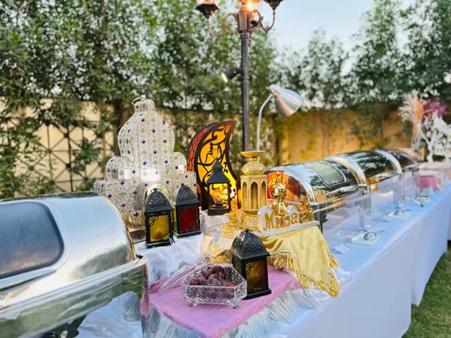 Ramadan catering station with covered dishes and decorative lanterns.