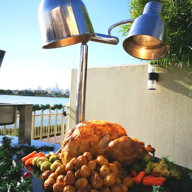 Roast and vegetable platter presented beneath a carving-station lamp.