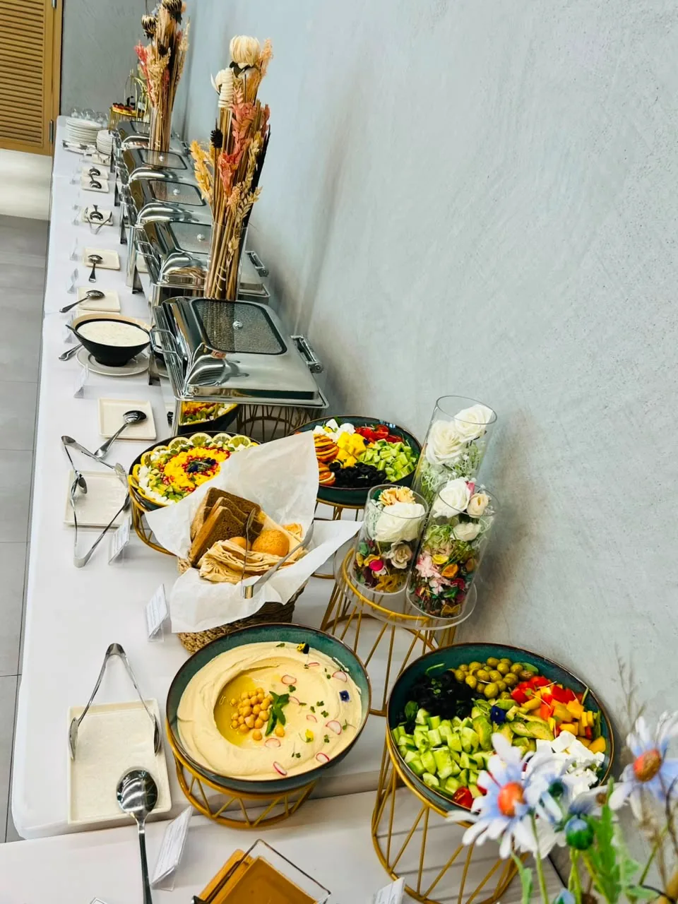 Styled buffet with a floral centrepiece, salads and serving bowls.