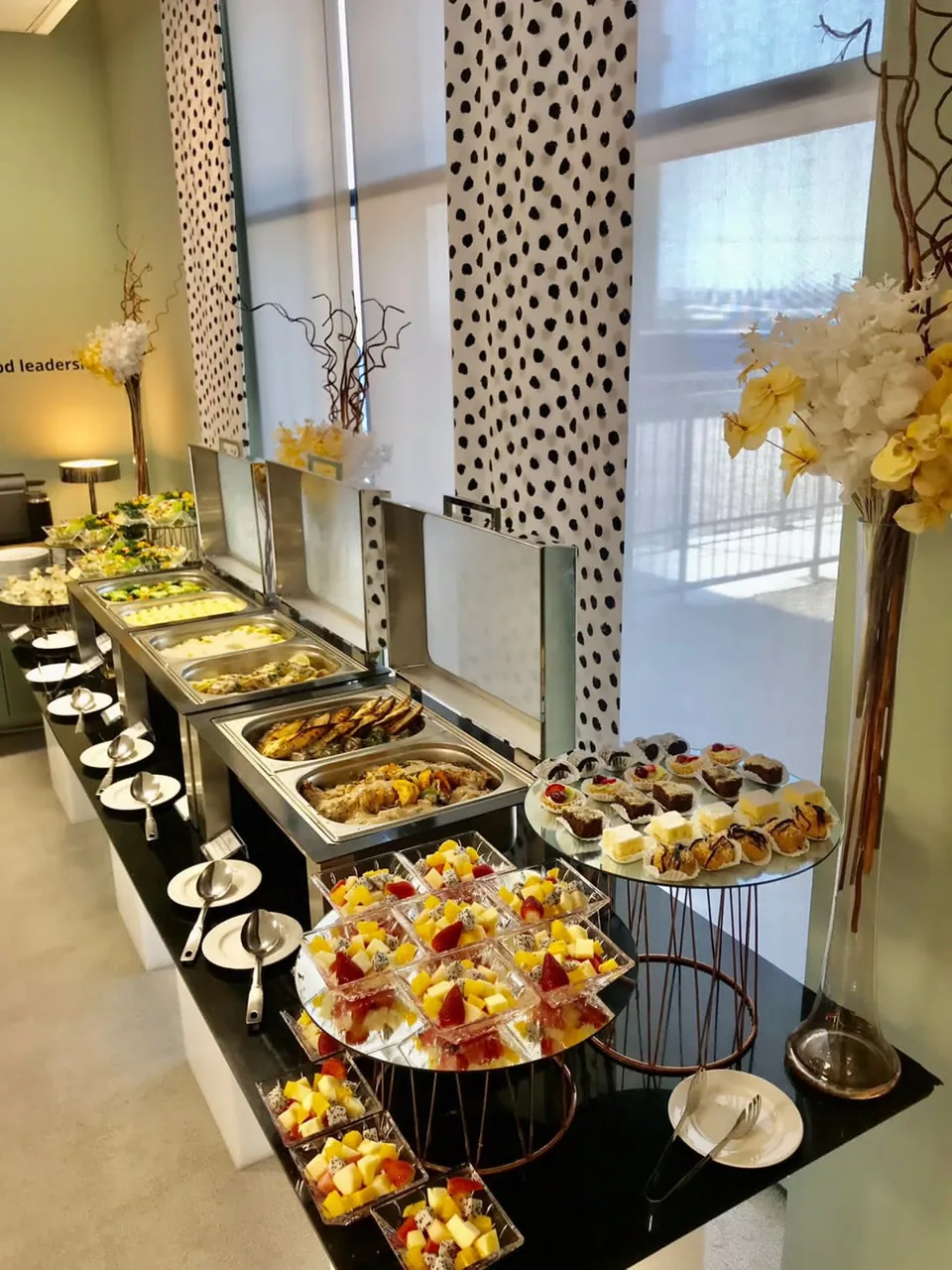 Styled buffet with a leafy centrepiece and decorative serving stands.